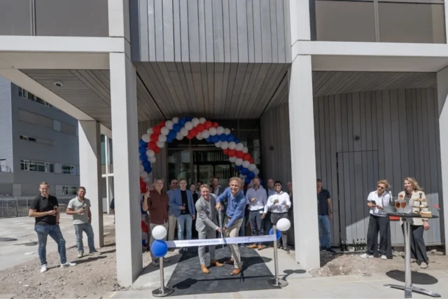 Medewerkers van het OLVG lab voor de ingang van het nieuwe gebouw. Een lint om door te knoippen. Ballonnen.