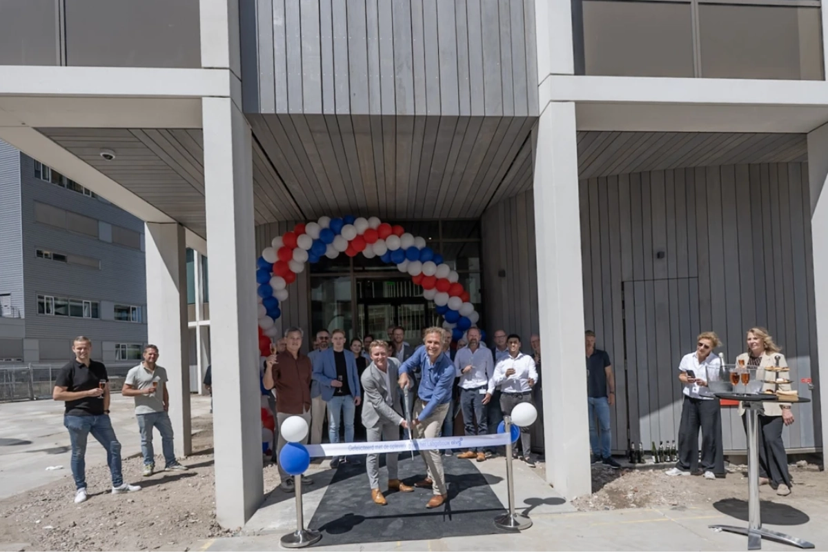 Medewerkers van het OLVG lab voor de ingang van het nieuwe gebouw. Een lint om door te knoippen. Ballonnen.